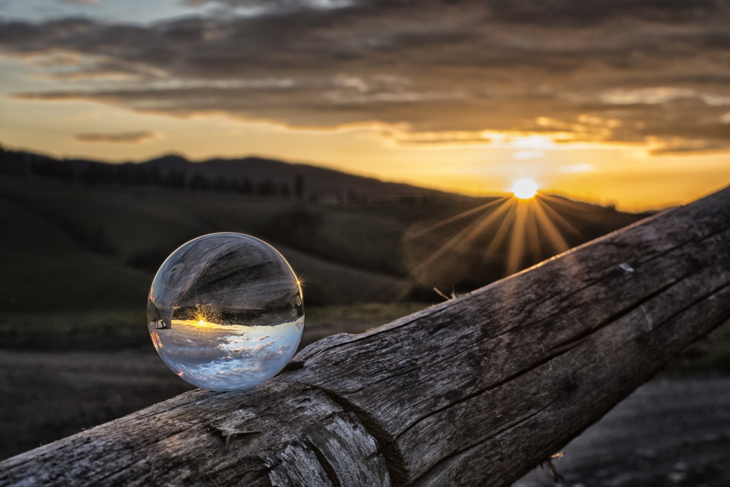 Tramonto sulle colline toscane con una sfera di vetro