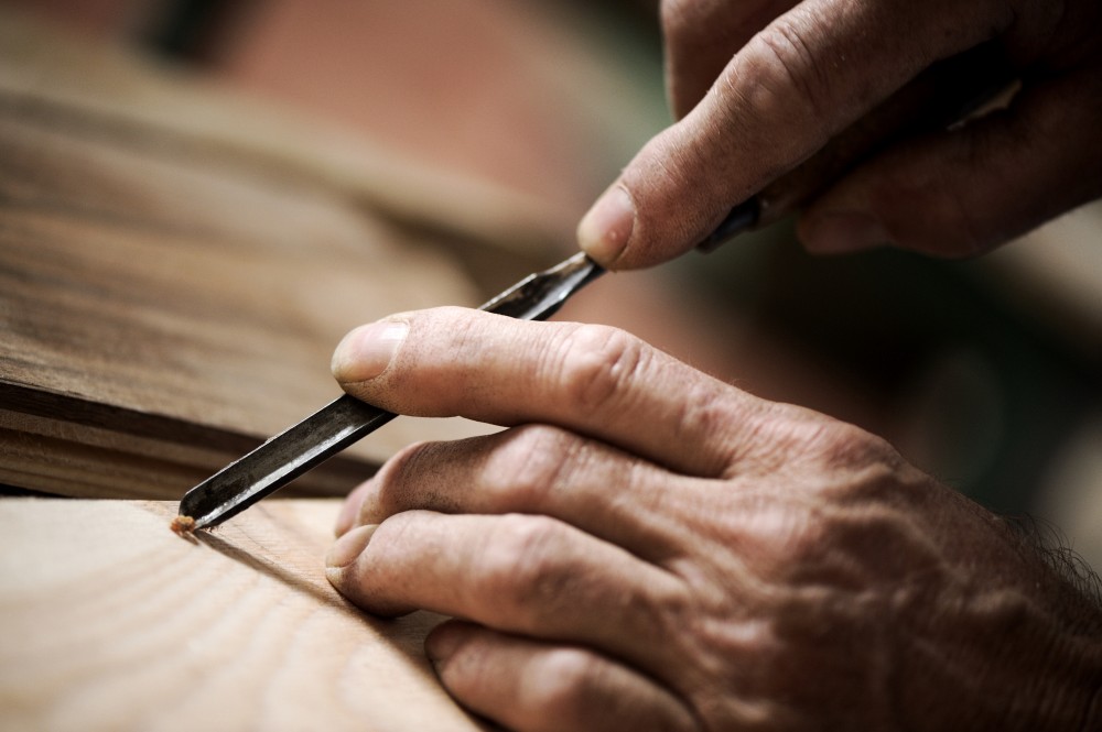 Mani di artigiano intagliano una tavola di legno