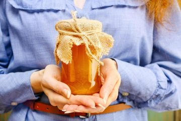 Ragazza tiene in mano un vasetto di miele toscano