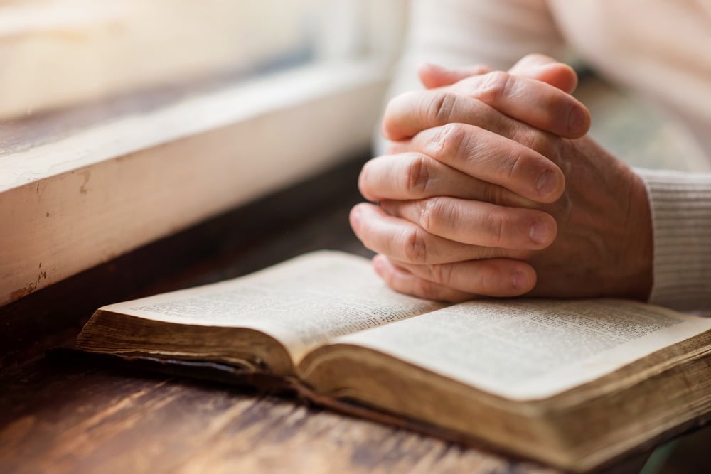 Un libro di preghiere con mani giunte