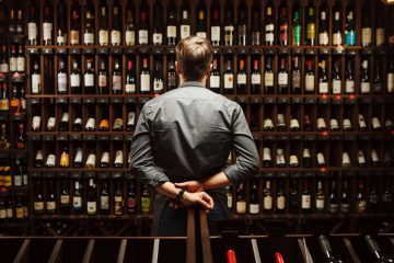 Uomo di fronte a bottiglie di vini del senese