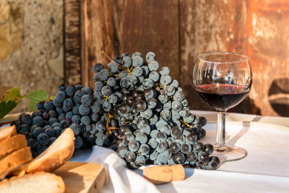 Bicchiere di vino rosso toscano accanto a grappolo d'uva