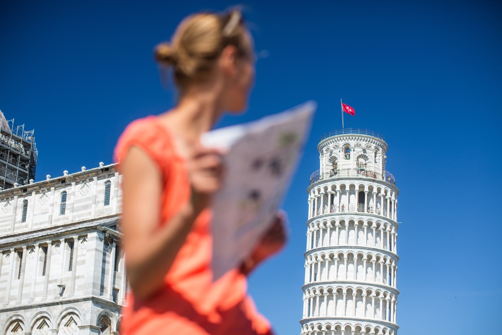 Turista con cartina di fronte alla Torre di Pisa