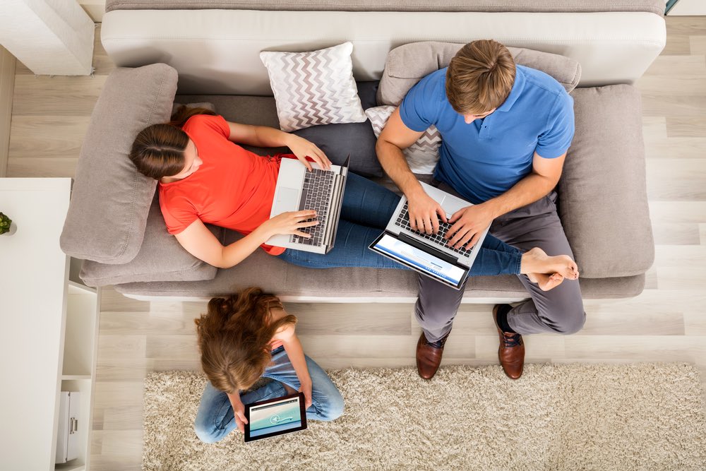Una famiglia sul divano utilizza tre computer 