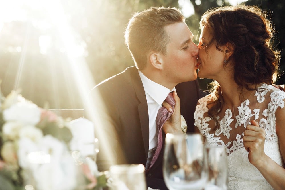 Una coppia di sposi si bacia durante il rinfresco di matrimonio
