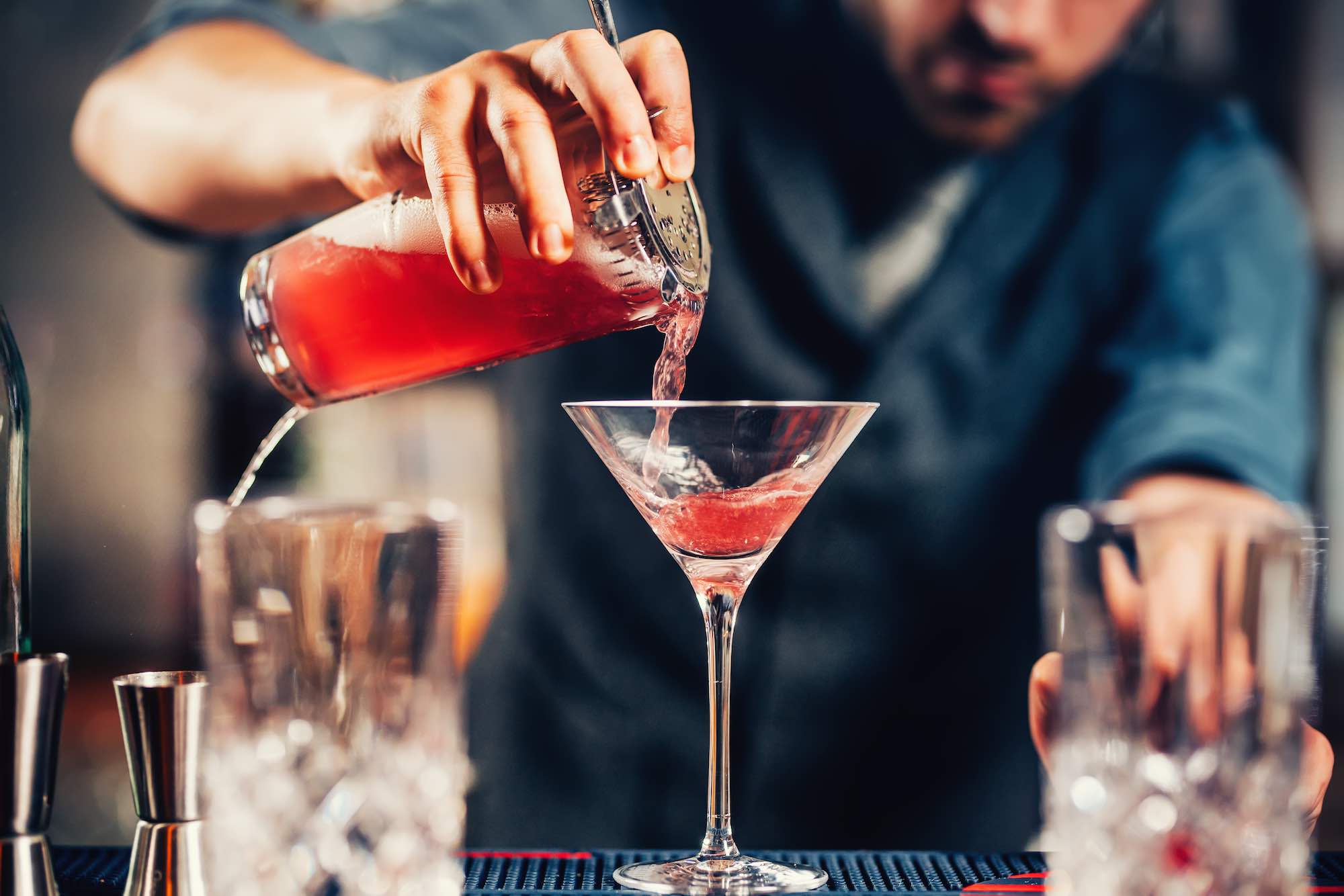 Barman versa in una coppa Martini un cocktail rosso
