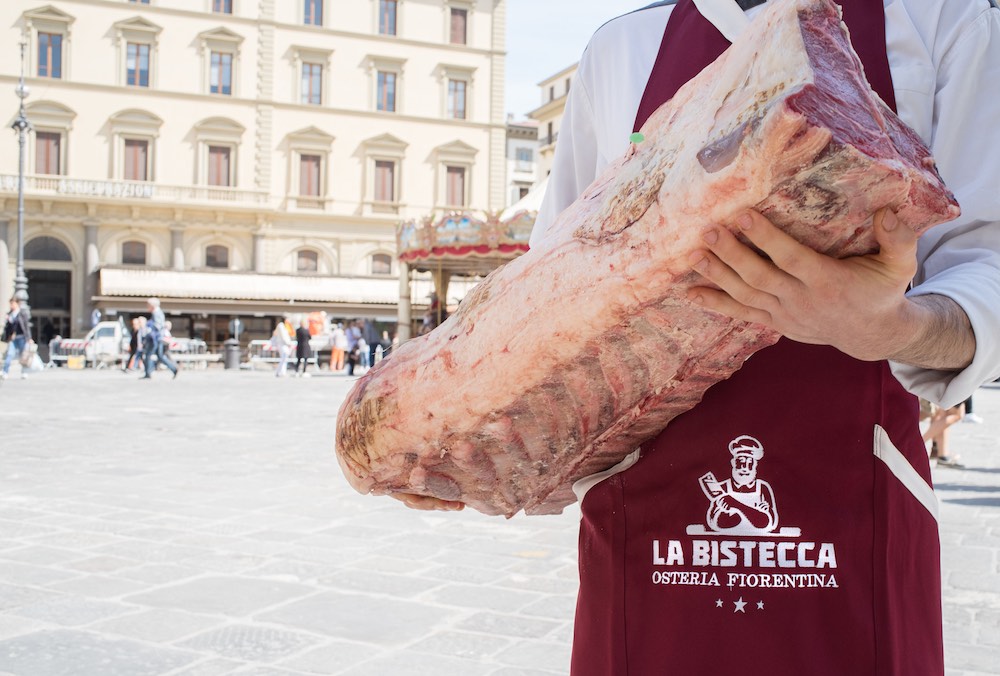 Cameriere de La Bistecca Osteria Fiorentina tiene in mano una costata