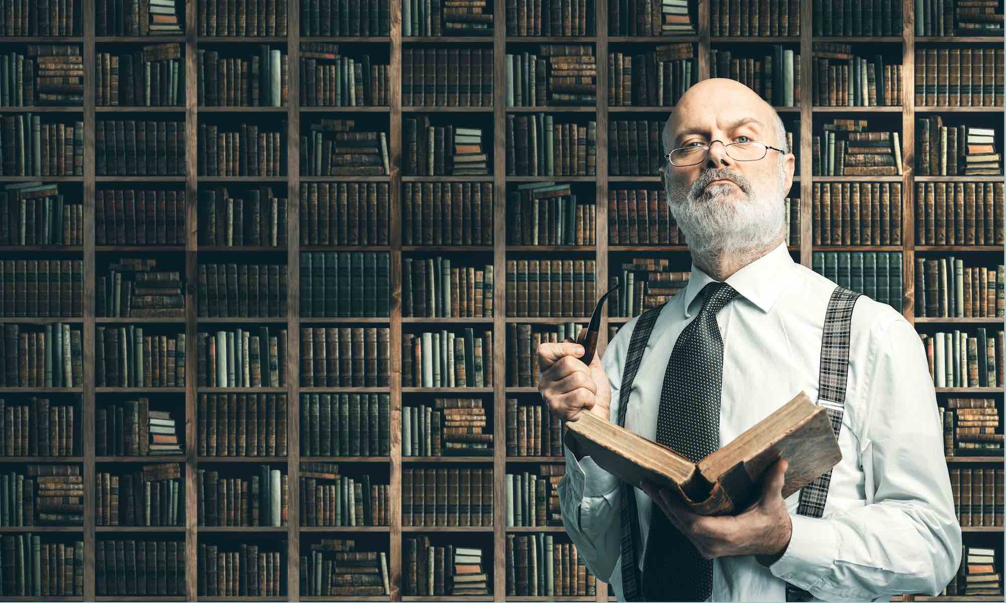 Signore con occhiali e libro in mano davanti a una libreria con molti tomi