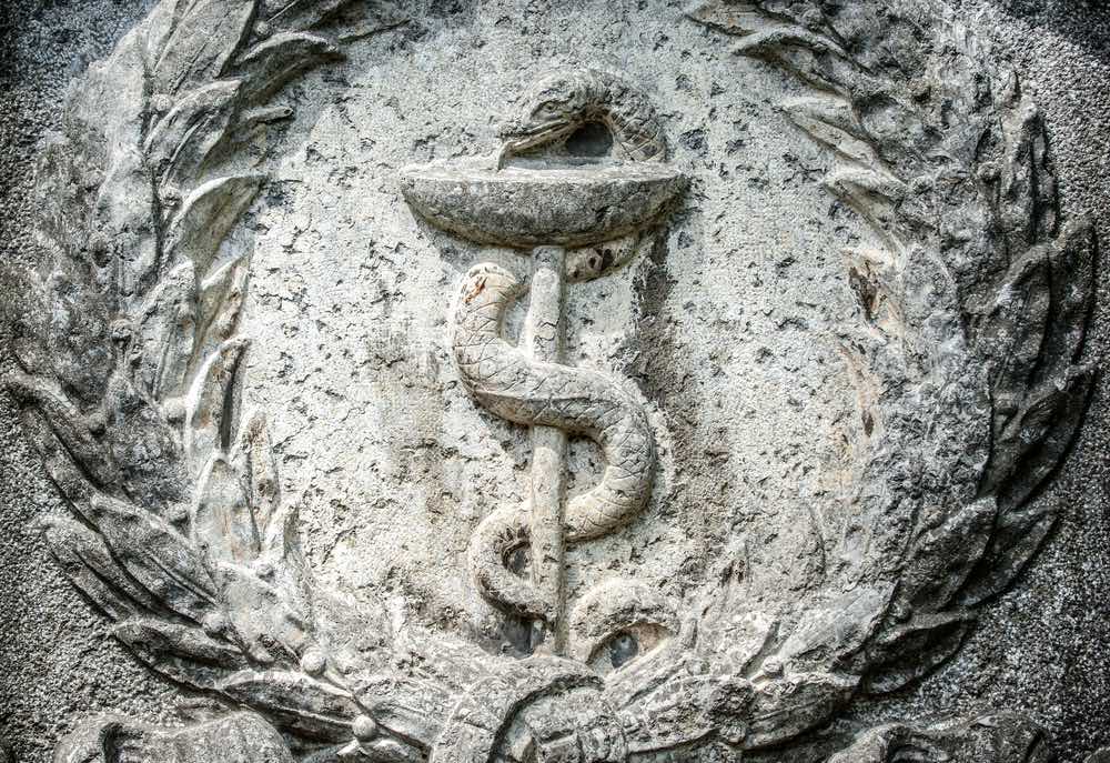 Il bastone di Esculapio, simbolo della medicina, scolpito su pietra
