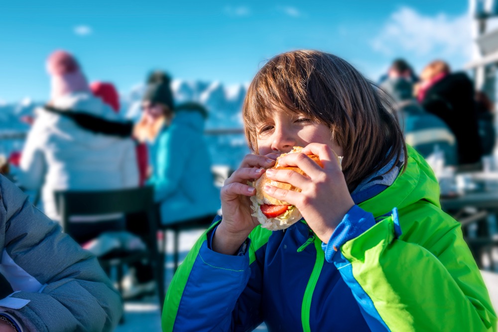 Bambino mangia un panino in un rifugio in Val di Luce, nella Montagna Pistoiese