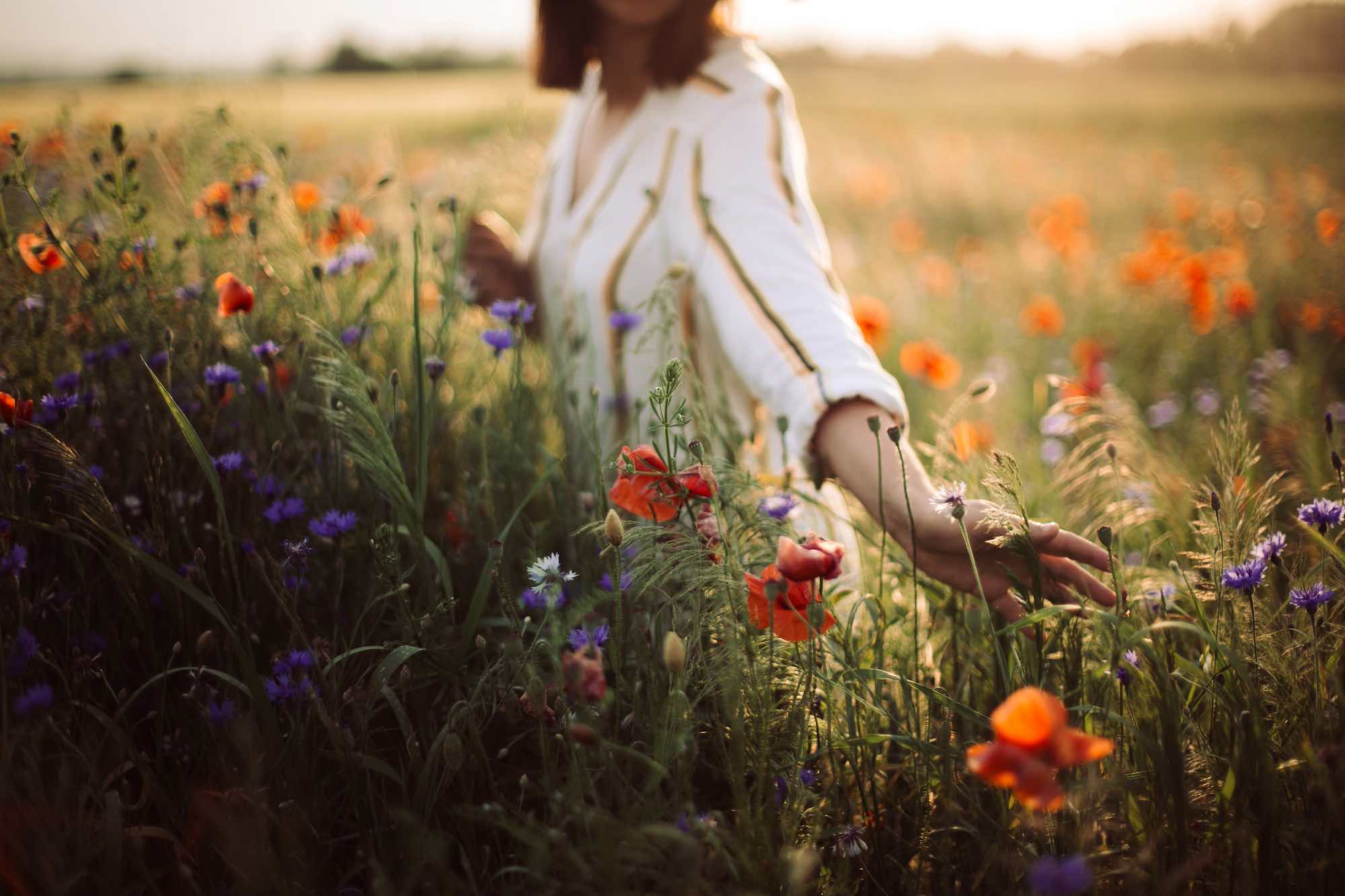 Ragazza cammina in un campo di fiori in estate, concetto di slow life