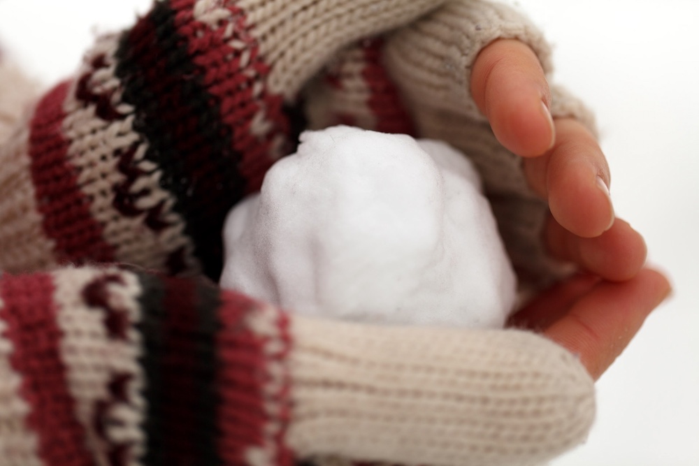 Palla di neve in mano a una ragazza con guanti lana
