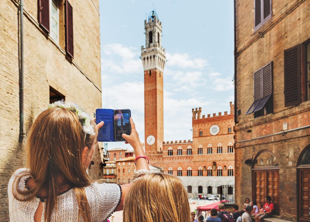 Bambini che fanno foto con lo smartphone di Piazza del Campo, Siena, Toscana