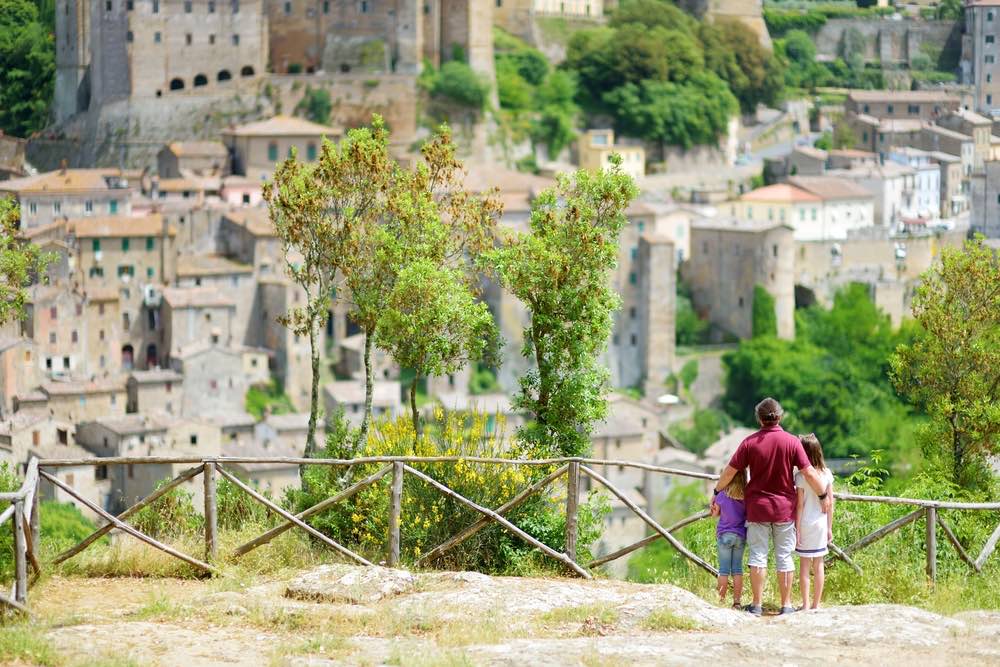 Famiglia di tre persone che si godono la vista di Sorano, antico borgo medievale toscano