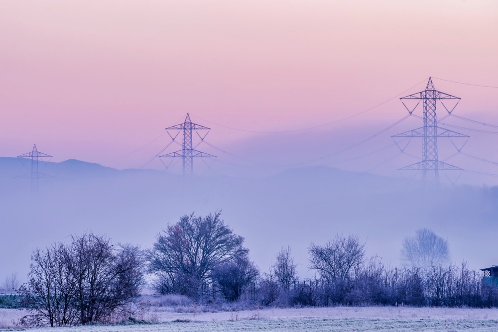 Piloni elettrici in Toscana coperti di nebbia e inquinamento all'alba