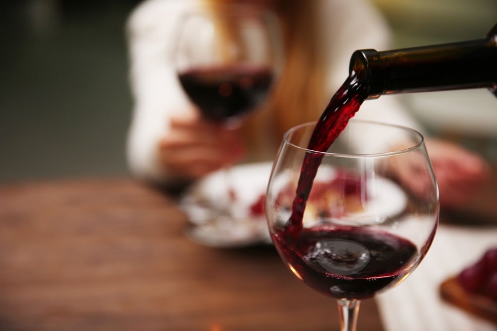 Vino rosso versato dalla bottiglia in un bicchiere