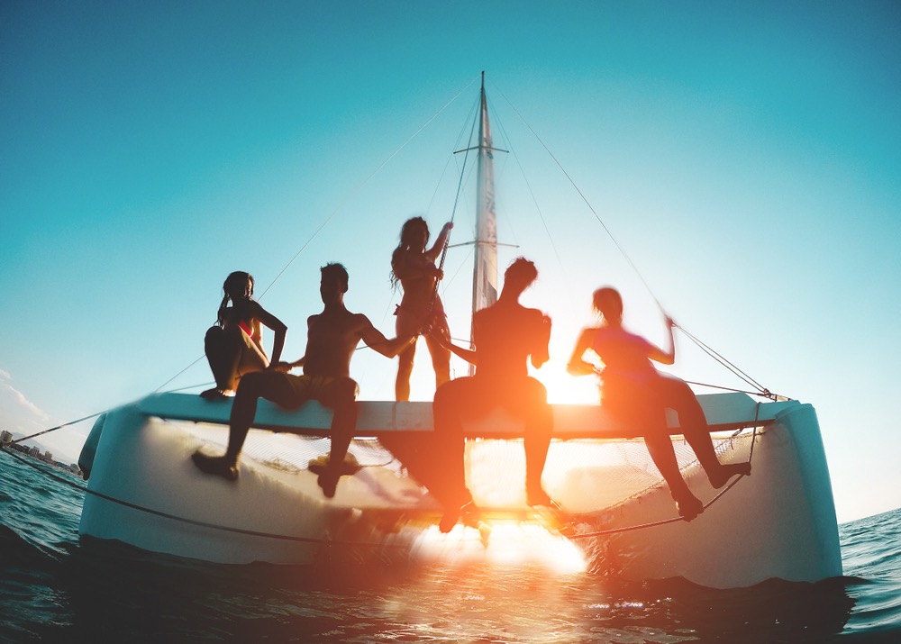 Gruppo di amici noleggia una barca e viaggia al tramonto