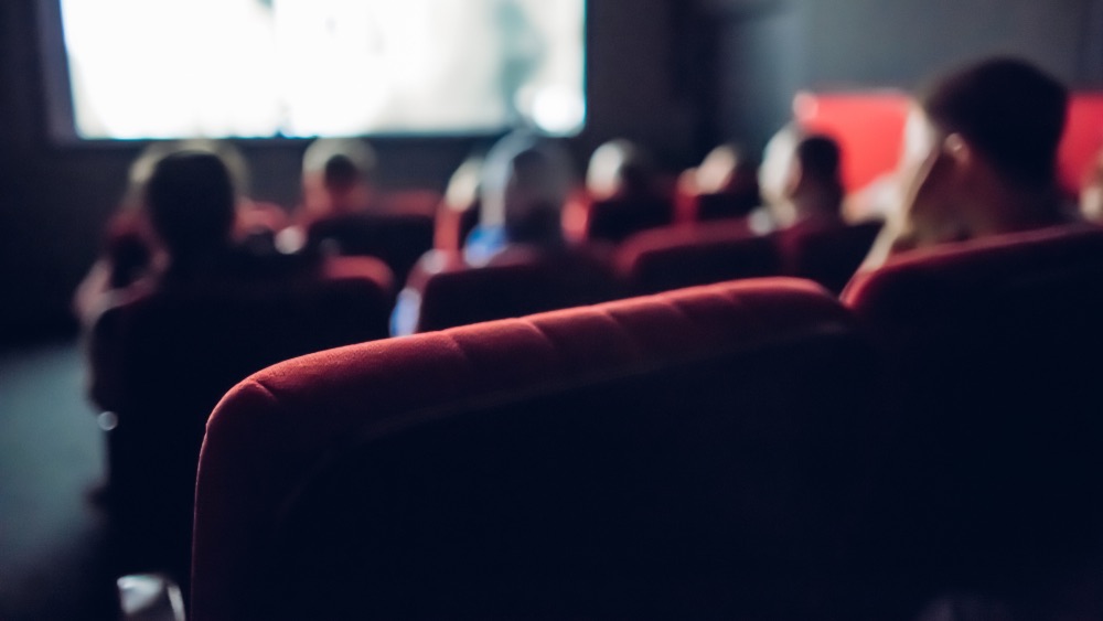 Interno di un cinema durante proiezione con poltroncine rosse