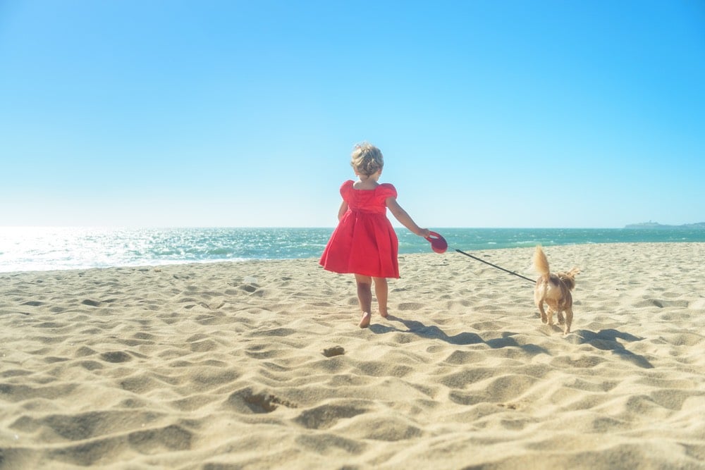 Bambina con cane in spiaggia pet friendly in Toscana