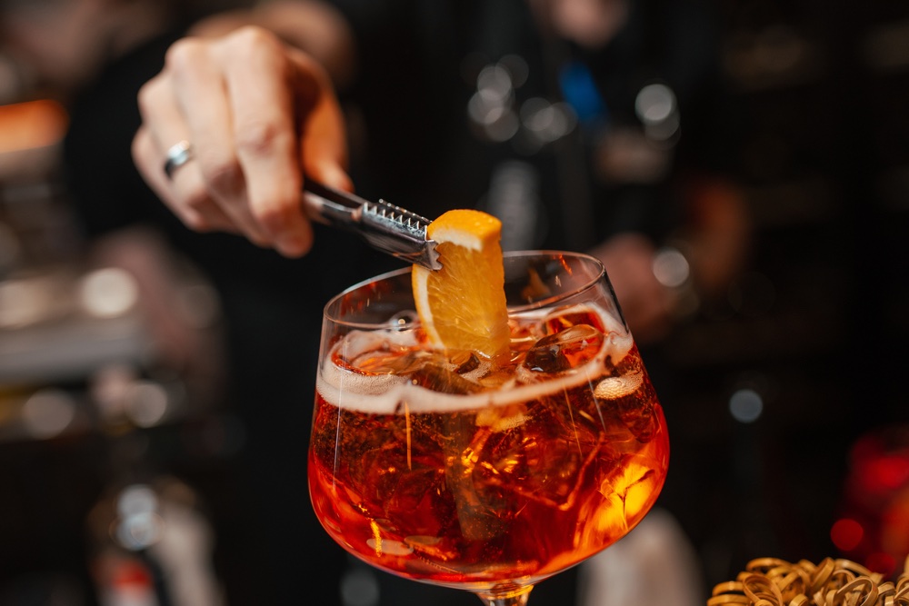 Barman mette fetta d'arancia in un bicchiere di cocktail Spritz