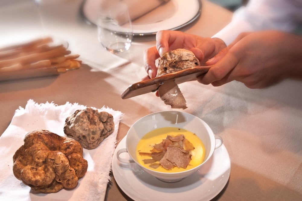 Cameriere gratta tartufo bianco in una terrina in un ristorante in Toscana