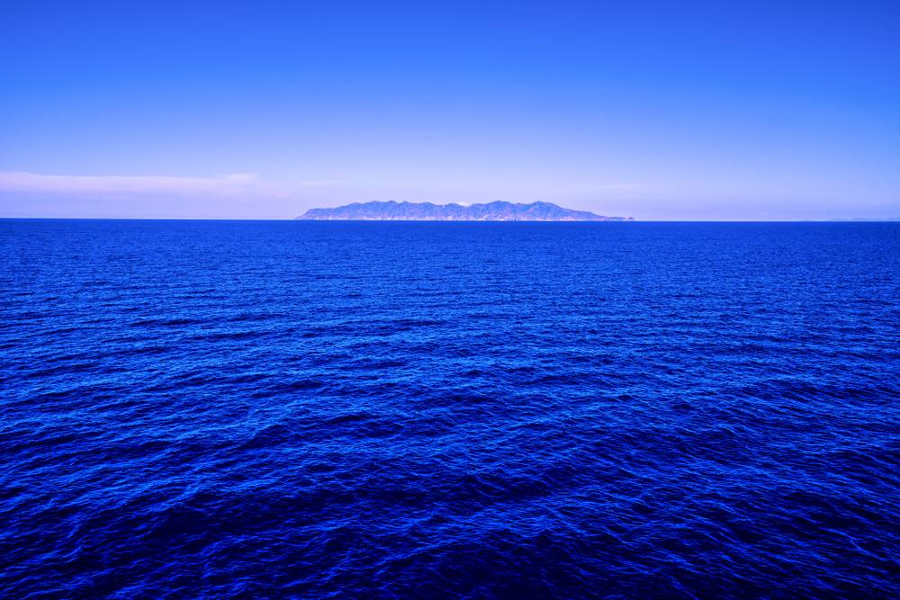 L'isola di Capraia vista da lontano nel blu del Tirreno in una giornata di sole