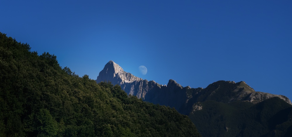 Luna nascente dietro le Alpi Apuane vicino al paese di Gragnola