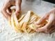 Farina sulle mani della chef che tira la pasta a un corso di cucina in Toscana