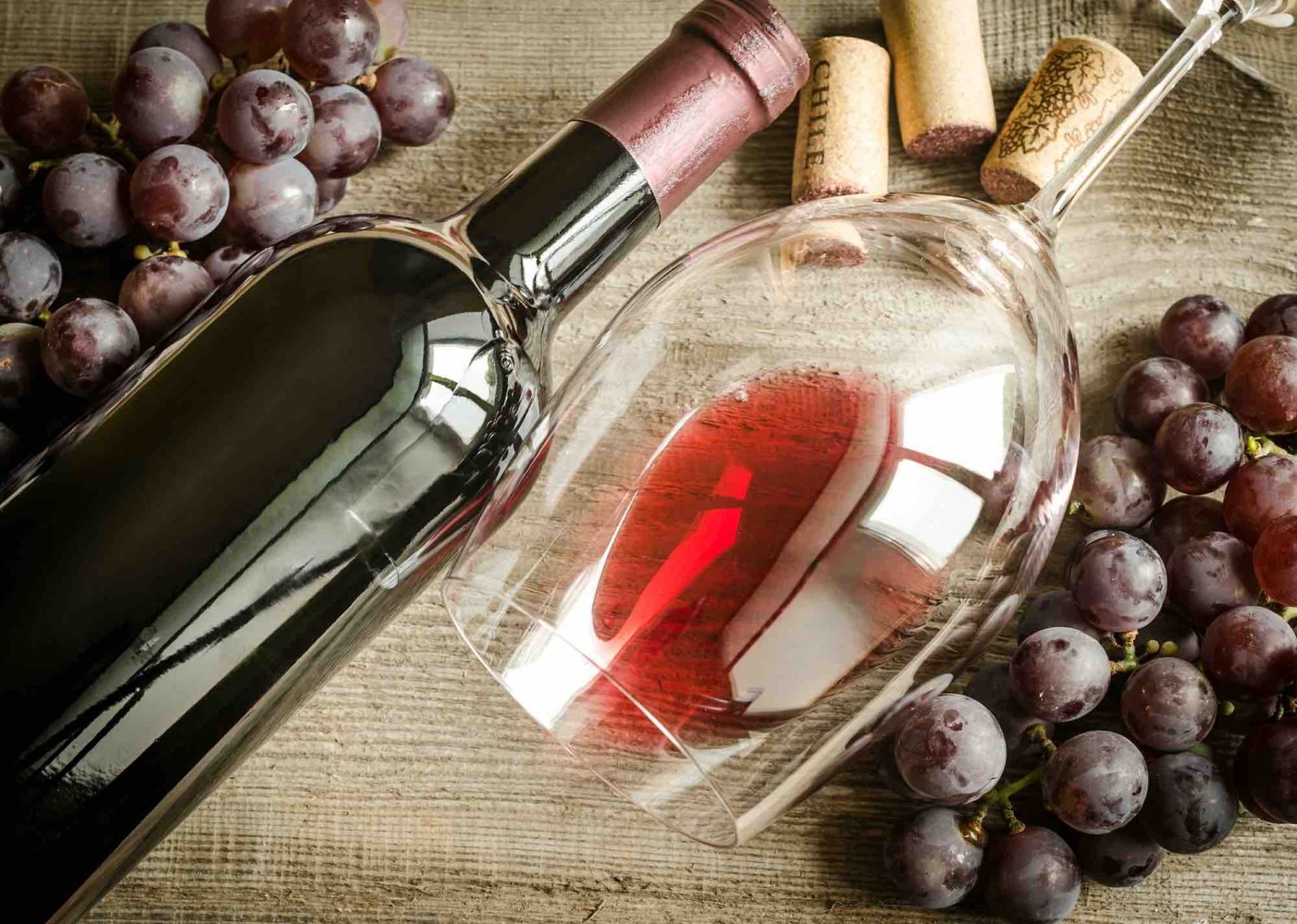 Bottiglia di vino rosso senza solfiti aggiunti, con bicchiere e grappoli d'uva