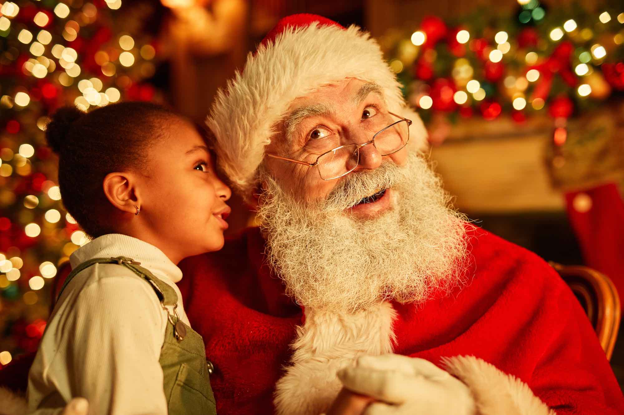 Ritratto di bambina che sussurra richieste a Babbo Natale alla vigilia di Natale