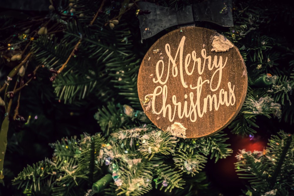 Merry Christmas scritto su legno tra rami di abete