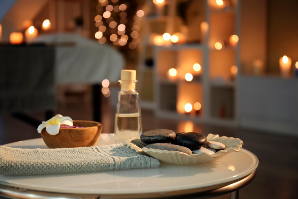 Pietre da massaggio, asciugamano e olio essenziale sul tavolo del salone termale