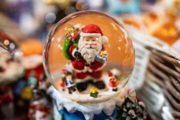 Palla di vetro natalizia con Santa Claus che porta i doni