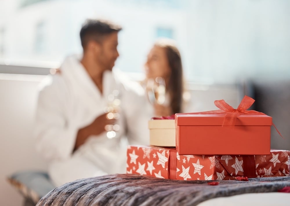 Regalo di Natale, regalo e coppia felice che festeggia le vacanze in hotel con lo champagne. 