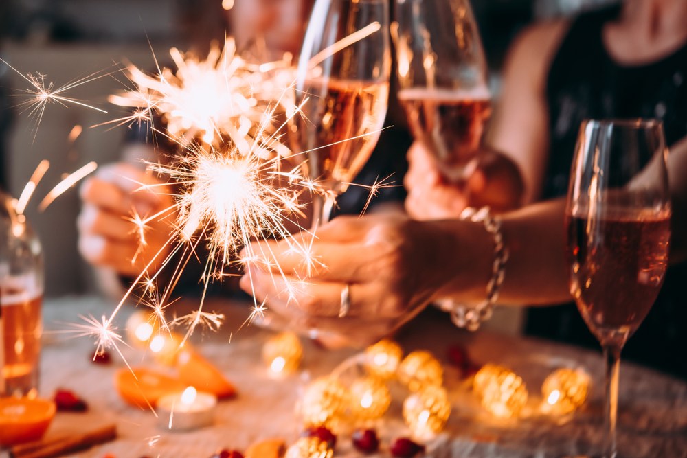 Amici che festeggiano il Natale o il Capodanno con luci bengala e champagne rosé.