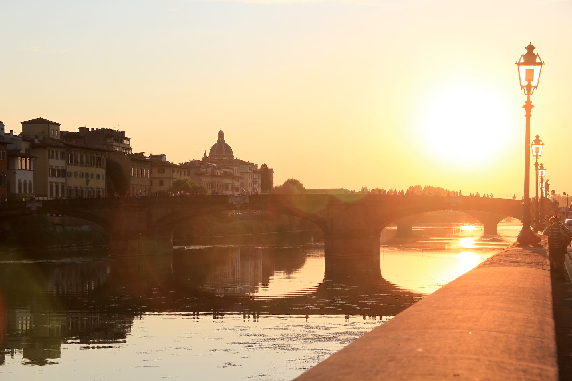 Tramonto sul fiume Armo tra i ponti di Firenze con sagoma di lampioni e Cupola del Cestello