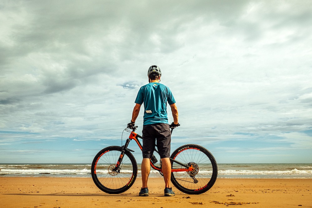 Ragazzo con mountain bike sulla spiaggia