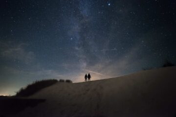 Due persone guardano il cielo stellato all'imbrunire