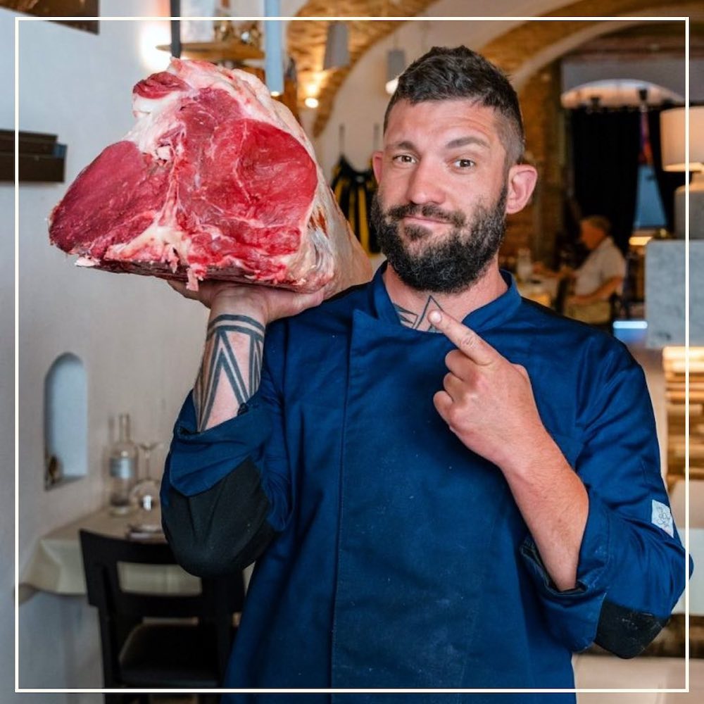 Chef della Trattoria i Fratellini a Firenze con in mano una costata di manzo per fare la bistecca