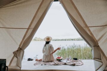 Ragazza seduta fuori dalla tenda in un camping sul lago