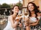 Due ragazze brindano con un calice di vino bianco in terrazza