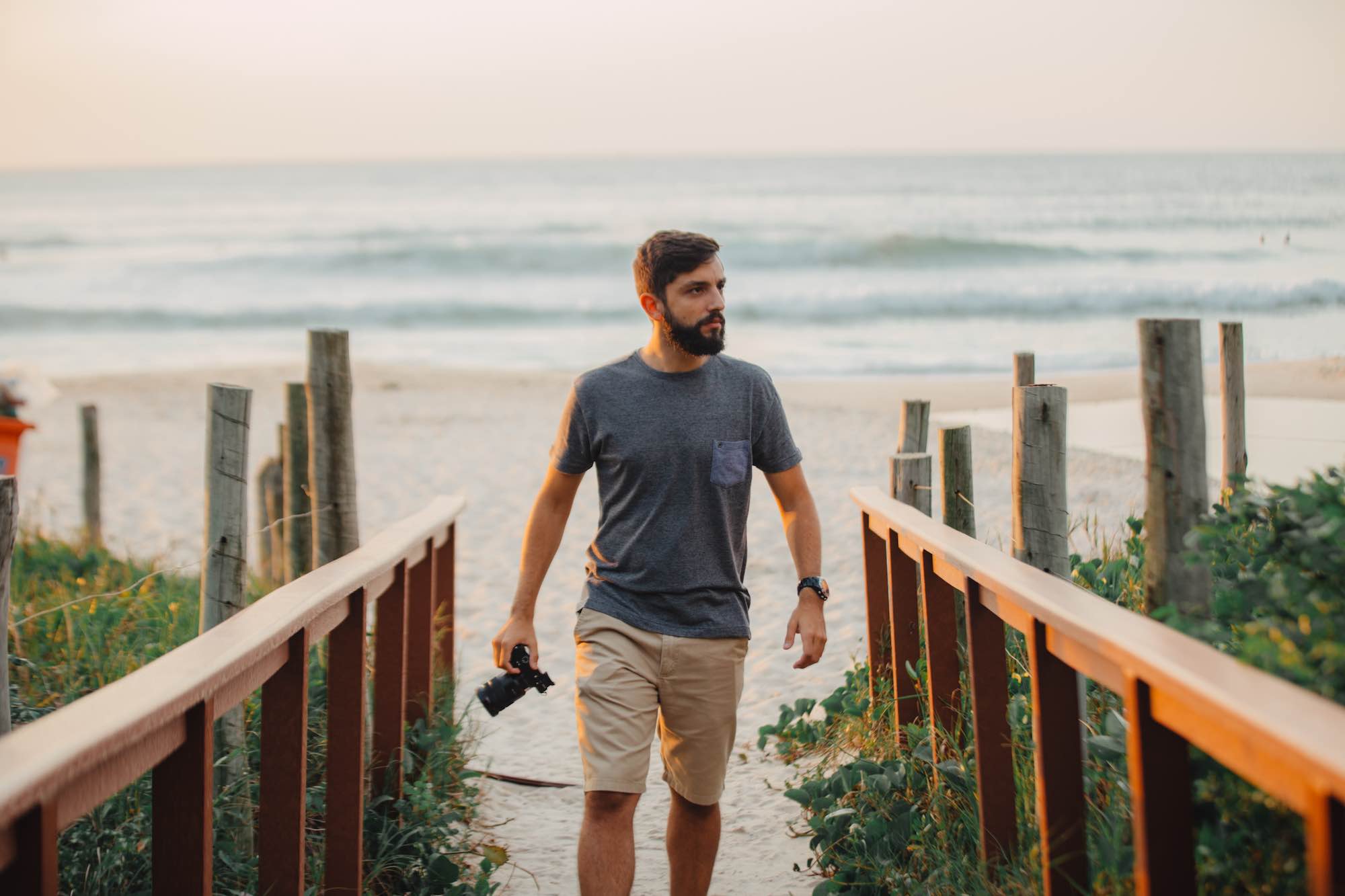 Fotografo cammina su spiaggia con macchina fotografica