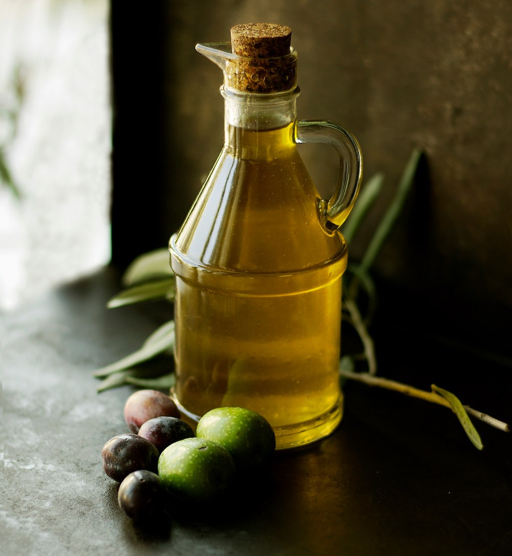 Bottiglia di olio nuovo di oliva con delle olive