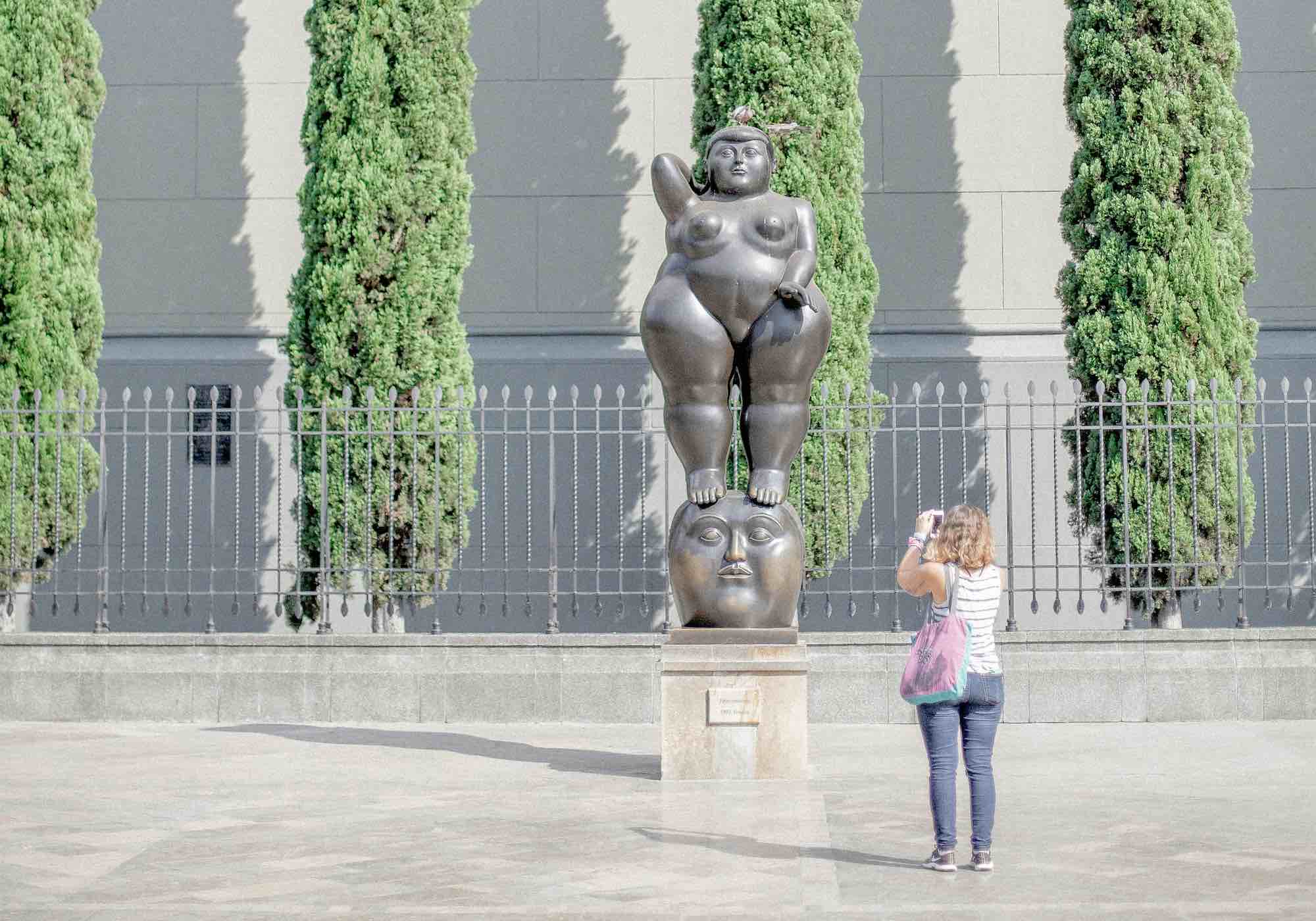 Donna fotografa una statua di Fernando Botero in una piazza