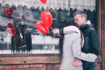 Una coppia si bacia davanti a una vetrina per San Valentino